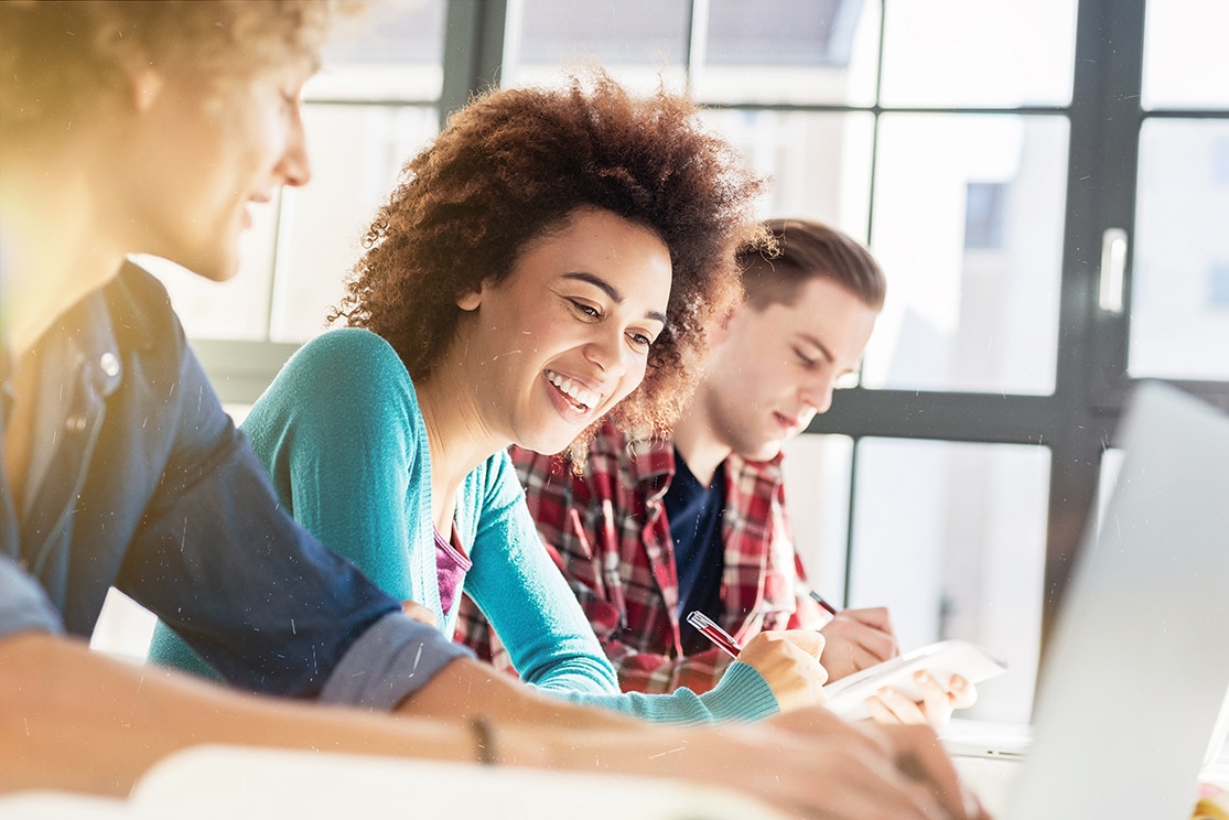 Studierende sitzen am Tisch und schreiben
